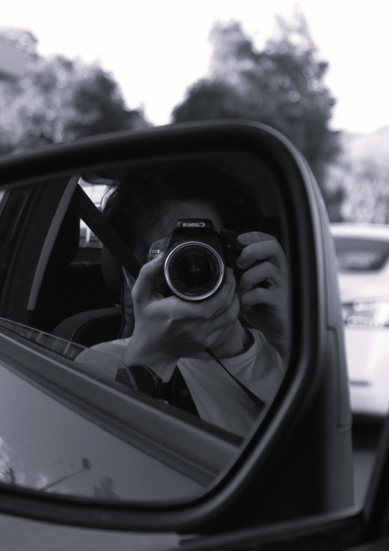 David Kim photographing in a car side mirror
